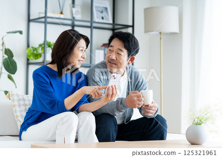 A middle-aged couple watching a smartphone in the living room A middle-aged couple watching a smartphone in the living room 125321961