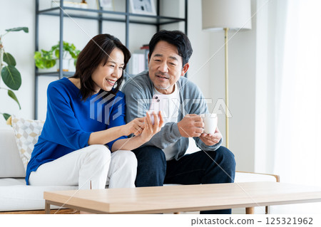 一對中年夫婦，在客廳裡看著智能手機 125321962