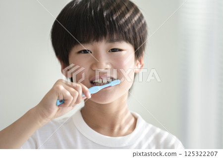 9-year-old boy brushing his teeth, looking at the camera 125322207