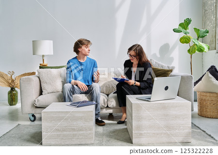 Teenage boy talking to female professional psychologist counselor therapist 125322228
