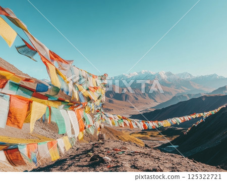 Colorful Buddhist flags waving in the wind against a clear blue sky or mountainous background, symbolizing peace and spirituality 125322721