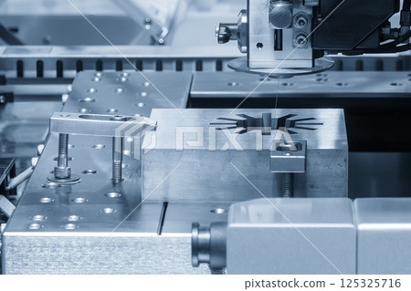The die insert cutting process by wire EDM machine control by CNC program in the light blue scene. Closeup scene the wire EDM machine cutting the mold insert parts. 125325716