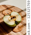 sliced green apple in drops of water on a white plate 125325769