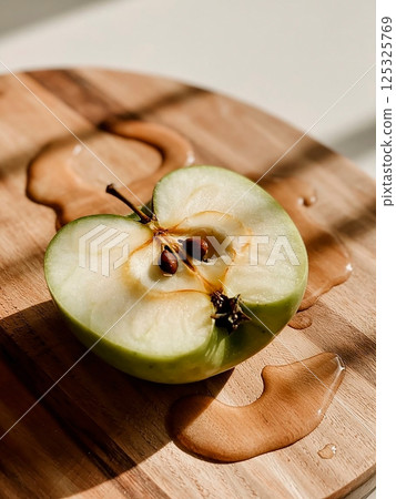 sliced green apple in drops of water on a white plate 125325769