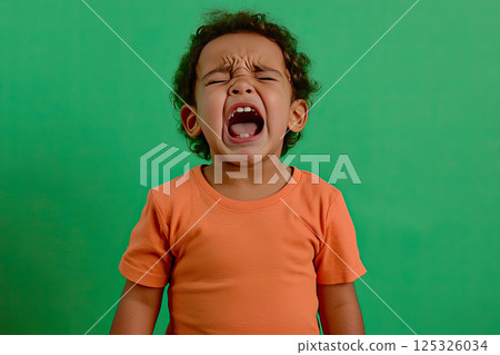 portrait of a crying child on a green background 125326034