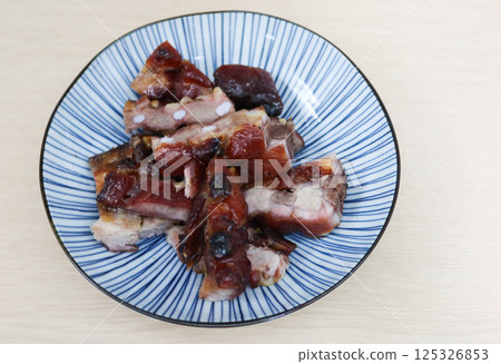 Close up of Cantonese Siu Mei grilled pork spare ribs on a plate with copy space on a blue plate 125326853