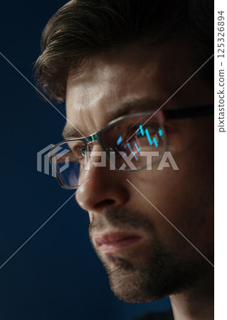 trader analyzes stock market with financial graphs reflecting in his lenses 125326894