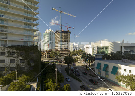 Tower lifting cranes at high residential apartment building construction site. Real estate development in Miami urban area 125327086