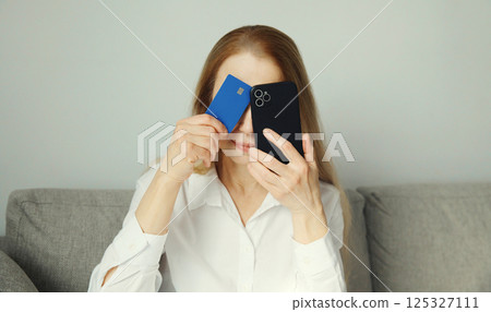 Upset young woman with smartphone, credit bank card, internet fraud, problems with online payments 125327111