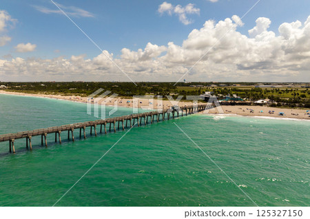 Summer landscape at Venice fishing pier in Florida. Ocean surf waves crashing on warm sandy beach 125327150