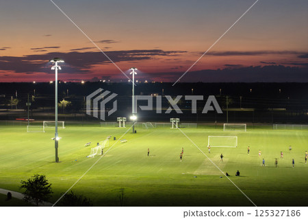 Sportsmen training in soccer game on illuminated football stadium in public sports park in North Port, Florida 125327186