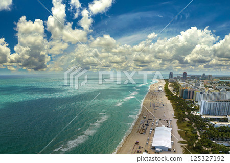 South Beach sandy surface with tourists relaxing on hot Florida sun. Tourism infrastructure in southern USA. Miami Beach city with high luxury hotels and condos 125327192