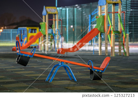 Seesaw swing in preschool yard with soft rubber flooring at night. 125327213