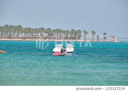 Seascape with ripple surface of blue sea water with white speedboat on anchor floating on calm waves 125327214