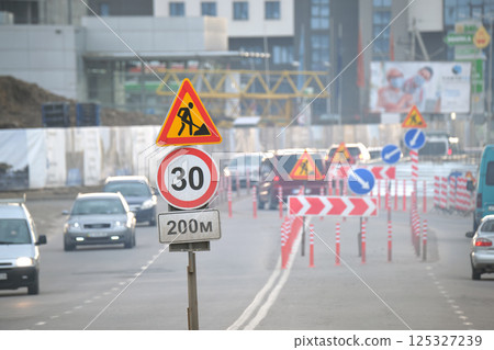 Roadworks warning traffic signs of construction work on city street and slowly moving cars 125327239