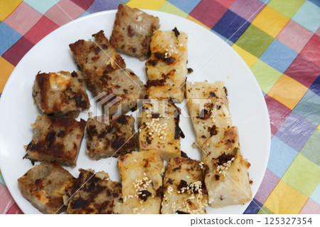 close up of traditional pan fried radish pudding cake and yam pudding cake cut in pieces dices on a white plate for Chinese Lunar New Year close up of traditional pan fried radish pudding cake and yam pudding cake cut in pieces dices on a white plate for Chinese Lunar New Year 125327354