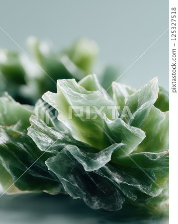 Raw green jade stone texture in close-up view with detailed mineral layers. Studio macro photography. Geology and crystal healing concept. Design for wallpaper, banner, print. Macro shot 125327518