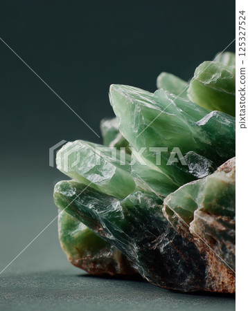Unpolished green jade crystal with visible natural striations and rough surface. Studio mineral photography. Geology and gemstone collection concept. Design for banner, poster, print. Macro shot 125327524