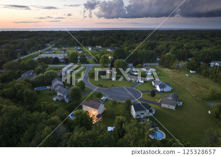 Residential illuminated homes at sunset in suburban sprawl development in Rochester, New York. Low-density two story private houses in rural suburbs. Housing market in the USA Residential illuminated homes at sunset in suburban sprawl development in Rochester, New York. Low-density two story private houses in rural suburbs. Housing market in the USA 125328657