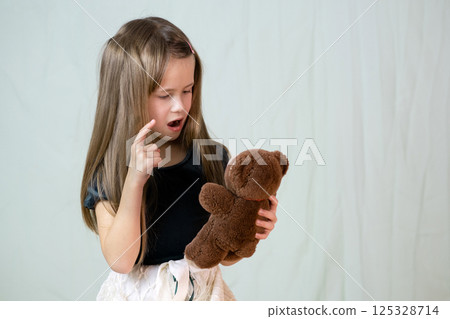 Pretty child girl playing with her teddy bear toy. Pretty child girl playing with her teddy bear toy. 125328714