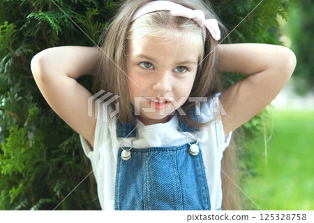 Portrait of pretty child girl standing outdoors in summer park smiling happily. 125328758