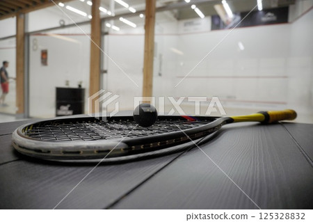 squash racket with ball close up, laying on table, preparing for game. court background, live pictures 125328832