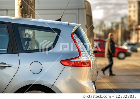 Modern cars parked on a side of a city street on a sunny day. 125328835