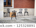 nice metal chairs with the wooden table near red brick building. cafe with eating outdoor 125328891