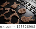 the Easter cookie dough and cookie cutters in bunnies and eggs share. children funny cooking close up on dark background 125328908