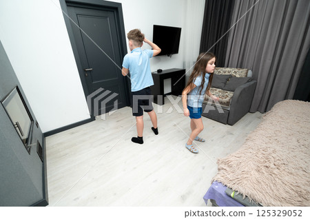 Children engaging in playful hide and seek in a cozy room filled with natural light and modern furnishings during a carefree afternoon Children engaging in playful hide and seek in a cozy room filled with natural light and modern furnishings during a carefree afternoon 125329052