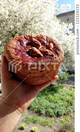 Ukrainian Paska Easter cake pie held in hand against blooming trees during springtime 125329153