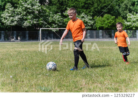 Two boys running after soccer ball on green field. Two boys running after soccer ball on green field. 125329227