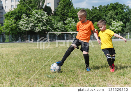 Two boys competing for soccer ball on green field. Two boys competing for soccer ball on green field. 125329230