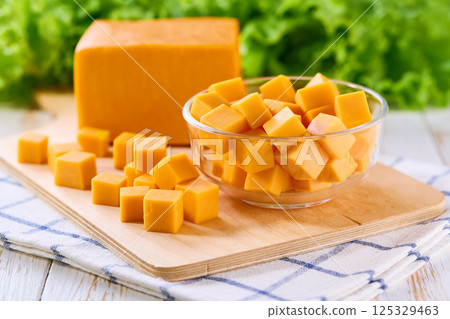 cheddar cheese cut into cubes on light kitchen table, selective focus. 125329463