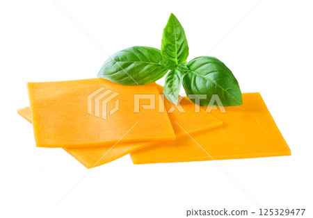 slices of tasty cheddar cheese and basil isolated on a white background. slices of tasty cheddar cheese and basil isolated on a white background. 125329477