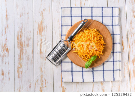 shredded cheddar cheese on a light kitchen table,copy space for text. Top view. 125329482