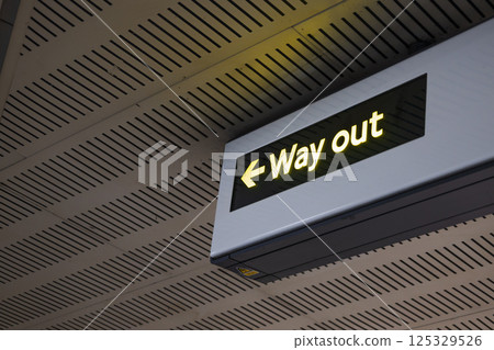 Illuminated Way Out Sign with Arrow in Modern Indoor Public Transportation Area 125329526