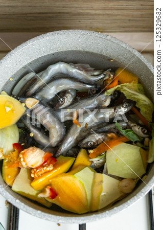 fish meal, large saucepan with sardine or capelin and vegetables. prepare healthy delicious food. 125329682