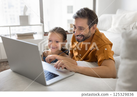 Happy single father preteen daughter using notebook at living room 125329836