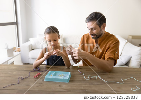 Friendly dad preteen daughter spend leisure time weaving decorative crafts 125329838