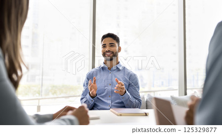 Happy smiling young businessman expert consult workmates at boardroom desk 125329877