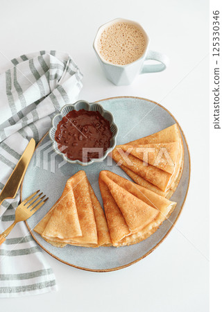 Crepes with chocolate cream and coffee on white wooden table. Pancake day, Maslenitsa. Top view Crepes with chocolate cream and coffee on white wooden table. Pancake day, Maslenitsa. Top view 125330346