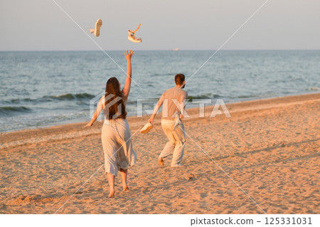 Girl throws sandals up in the ocean. Beginning of vacation, honeymoon Girl throws sandals up in the ocean. Beginning of vacation, honeymoon 125331031