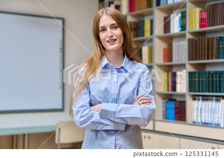 Portrait of teenage college student girl with crossed arms, inside library Portrait of teenage college student girl with crossed arms, inside library 125331145