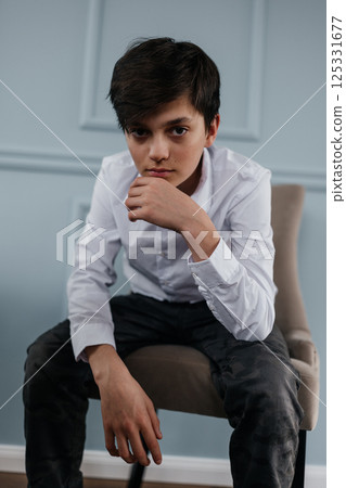 portrait of a handsome teenager sitting on the chair indoors portrait of a handsome teenager sitting on the chair indoors 125331677