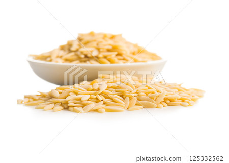 Orzo, kritharaki, risoni pasta. Uncooked dry pasta in bowl isolated on white background. 125332562