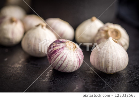 Solo glove garlic bulbs on black table. 125332563