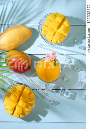 Summer party concept. Homemade cocktail, juice or lemonade with mango slices and ice on sunny kitchen table. Refreshing summer diet drink recipe, Detox diet and healthy lifestyle, Restaurant menu 125332572