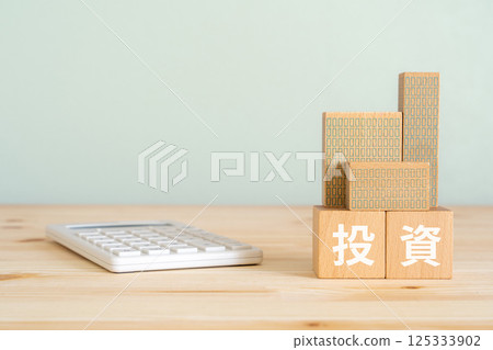Blocks with the word "investment" written on them, a model of a real estate property, and a calculator 125333902