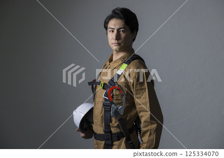 Male worker wearing a full harness 125334070